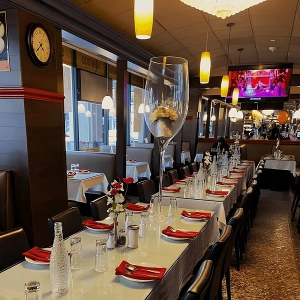 Long restaurant table set with red napkins and a giant decorative wine glass centerpiece.